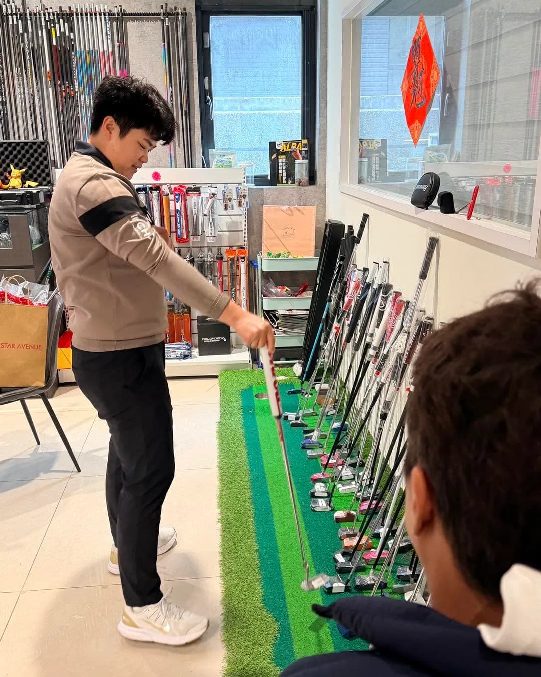 客人在方圓高爾夫門市內試推桿,旁邊是一整排推桿現貨